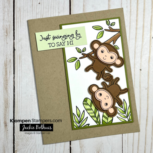 Handmade greeting card designed with the Stampin' Up! stamp set Little Monkey. Card is made with a Crumb Cake card base, has greenery stamped on Basic White cardstock that has been colored using Stampin' Blends, has two monkeys that were stamped and punched out using the coordinating punch, and a sentiment that reads "just swinging by to say hi."