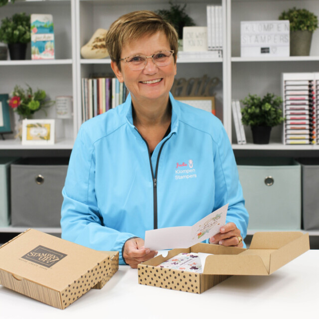 Picture of Jackie Bolhuis of Klompen Stampers standing at her crafting desk and opening card making crafting kits from the Stampin' Up! kits collection.