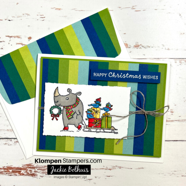 Christmas card designed with the Stampin' Up! Festive & Fun stamp set. Card images has a Rhino pulling a sled filled with presents, and has a greeting that says "Happy Christmas Wishes."