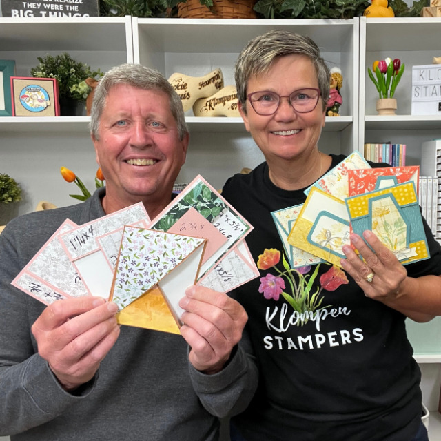 Jackie and Dave of Klompen Stampers holding fun fold card templates and completed fun fold cards from one of their class videos.