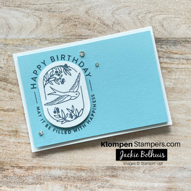 An easy birthday note card layout that is designed with the stamp set Filled with Happiness. The note card has a blue background, a happy birthday sentiment stamped in blue ink, and a blue bird that is punched out of white cardstock using an oval punch.