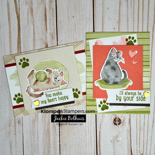 Two cards lying on a table. Both cards are different designs, made with the same brown, green, and pink colors. Each card features a different cat image with small paw prints stamped around them.