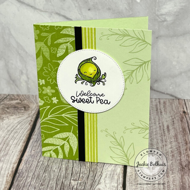 A handmade card with different green patterned papers and a colored in stamped image of a pea in a pod with a sentiment that reads "welcome sweet pea".