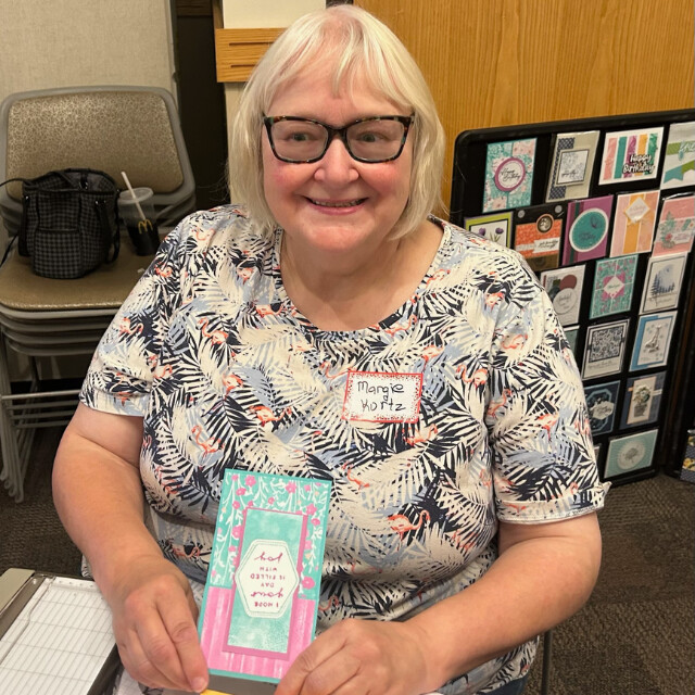 A Klompen Stampers Team member holding her mini slimline card create at a team event held in August 2024.