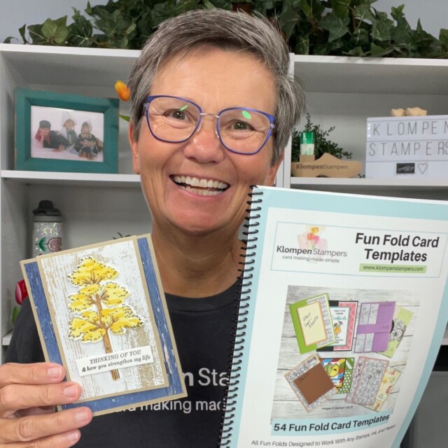 Jackie of Klompen Stampers holding her handmade card designed with the Frosted Forest Bundle that is a fun fold card. Which was inspired from her Fun Folds Template Book, which she is also holding.