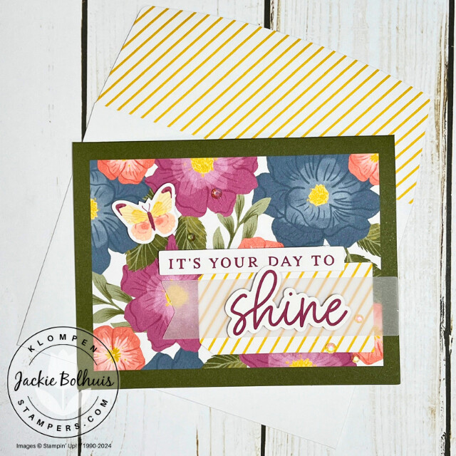 A handmade card with a floral printed card base, a small butterfly image, and a sentiment that reads "It's your day to shine" with the word shine large and in cursive.