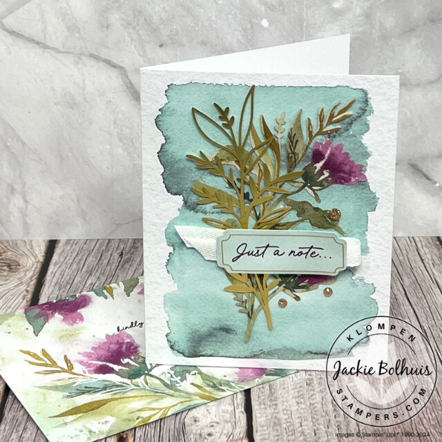 A heartfelt card to send a loved one for any occasion made from the Expression of Kindness card kit. Card has blue watercolor background, a purple flower, greenery, and sentiment that reads "just a note...".