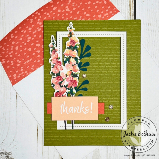 A handmade card designed with the Stampin' Up! Hello Hollyhocks card kit. Card base is green, there is a small white frame, a hollyhocks detail, and a sentiment that says "thanks!".