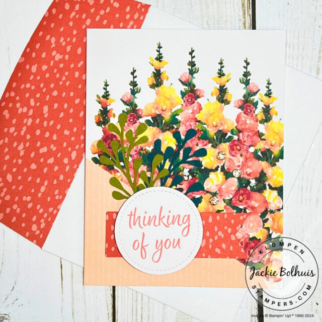 A handmade card designed with the Stampin' Up! Hello Hollyhocks card kit. Card base is printed with hollyhocks images and there is a sentiment that says "thinking of you" on a white circle.