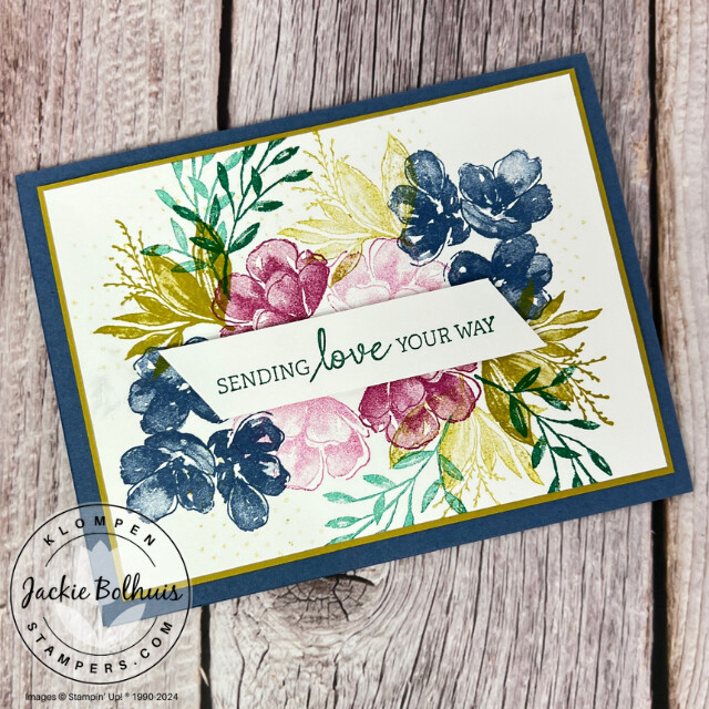 A colorful floral design stamped on white cardstock that is layered on a blue card base. 