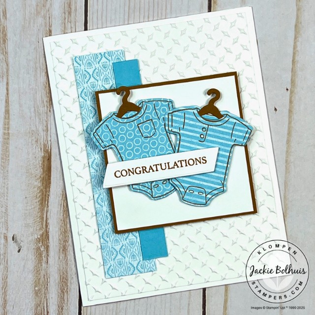 A baby card designed with the Stampin' Up! Cutest Onesie Bundle. Card layout is an easy template from the 48 Card Making Templates resource book. This card has a white card base, two blue stripes, and two blue onesies on hangers with a congratulations sentiment.
