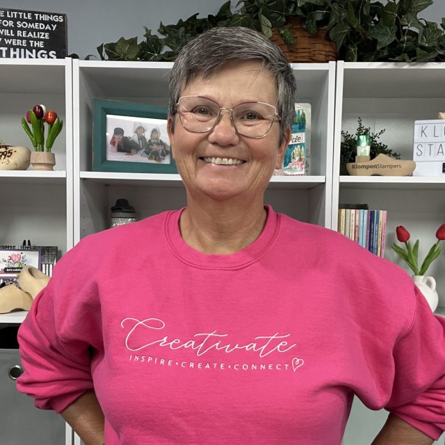 Jackie Bolhuis smiling and wearing a cozy pink Creativate sweatshirt, showing her Creativate team spirit.